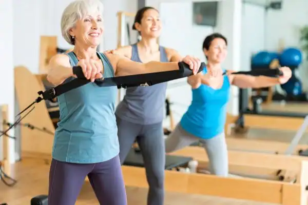 Toning Arms After 60: Empowering Womens Fitness Through Effective Weight Training 2 older woman doing weight training Wokingham and resistance in the gym to tone upper arms
