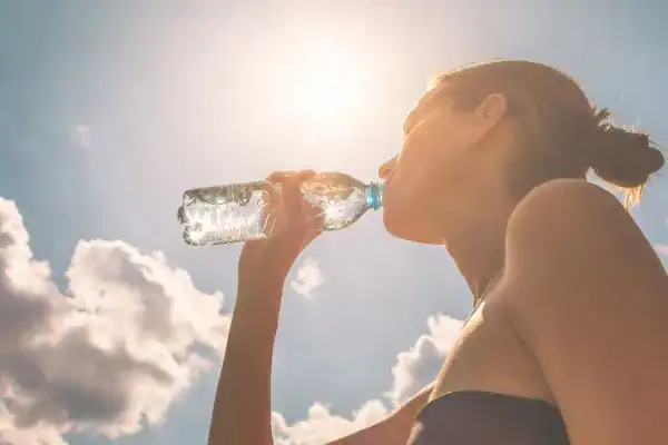 Hydration: The Secret Ingredient for a Toned Stomach and Enhanced Fitness 3 Image of woman drinking water to hydrate Wokingham after run.