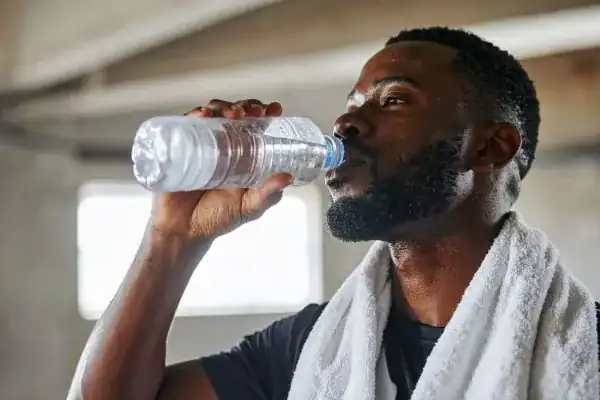 Hydration: The Secret Ingredient for a Toned Stomach and Enhanced Fitness 1 Image of man drinking water to improve hydration Wokingham after work out.